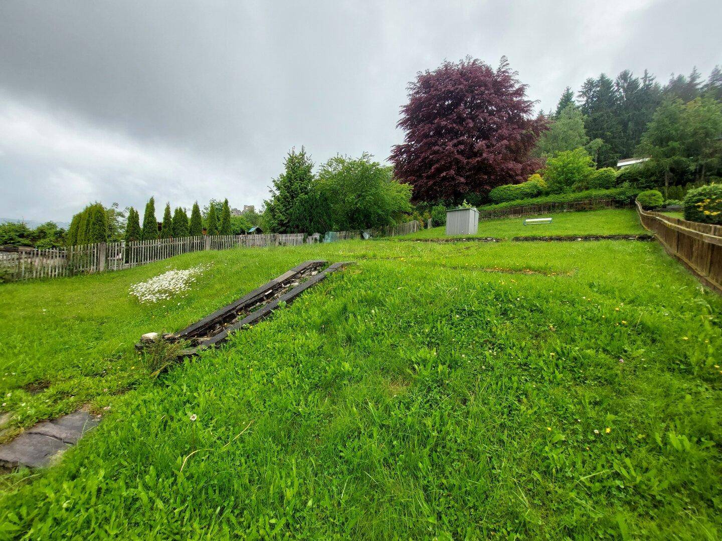 Weitläufiger Garten mit Rasenfläche und Blick auf die umliegende Landschaft und Bäume.