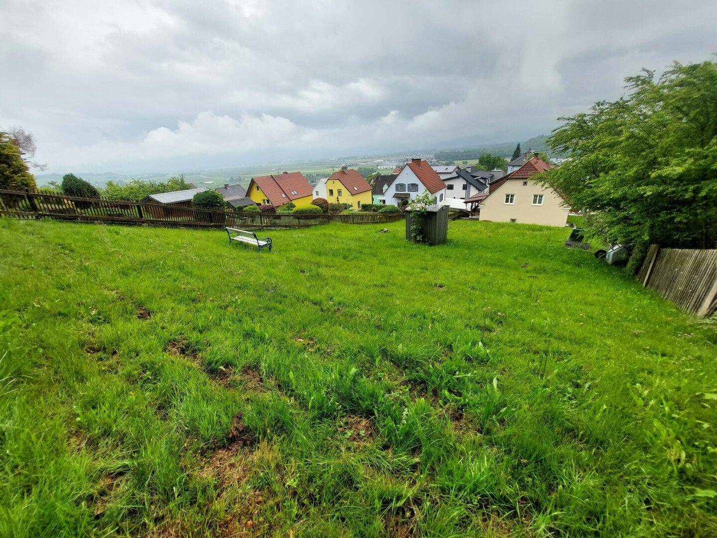 Großer Gartenbereich mit Sitzbank und weitem Blick über die Dächer der Nachbarschaft.