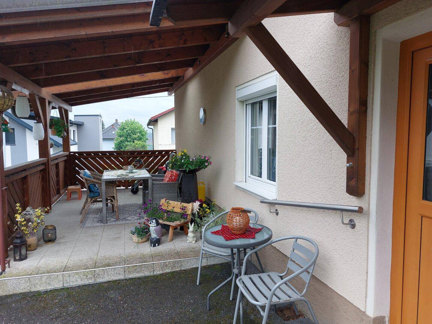Überdachte Terrasse mit Fliesenboden und Gartenmöbeln, ideal für entspannte Stunden.