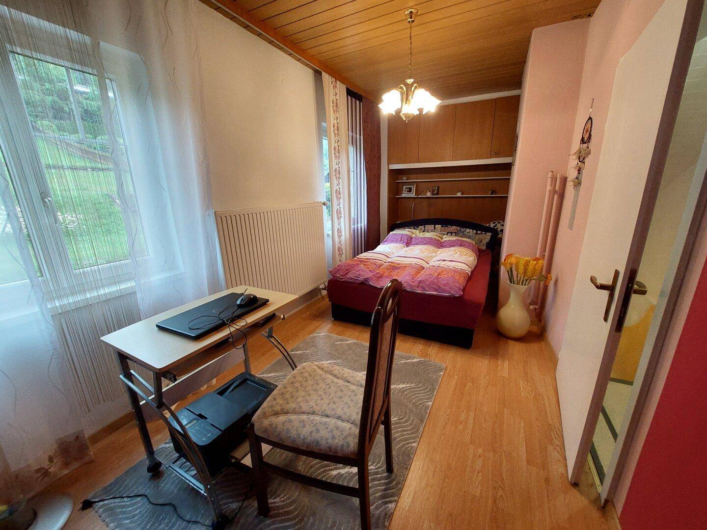 Schlafzimmer mit Einzelbett, Schreibtisch und Blick ins Grüne, hell und funktional.