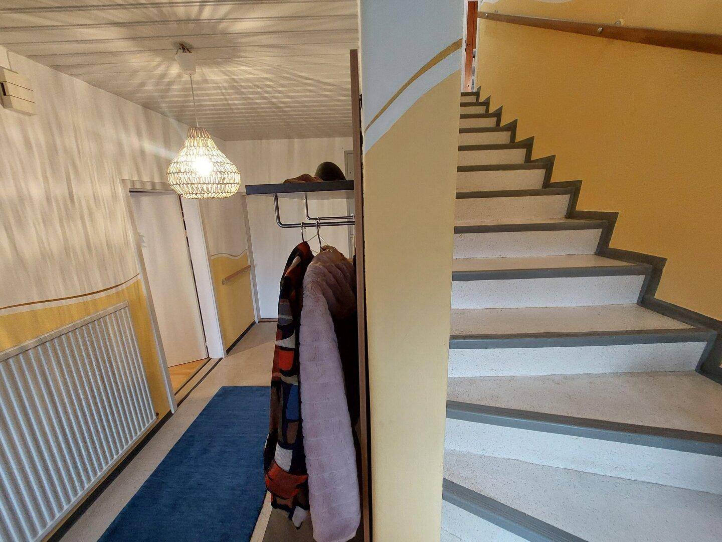 Heller Flur mit Treppenaufgang und Heizkörper, freundlich gestaltet.