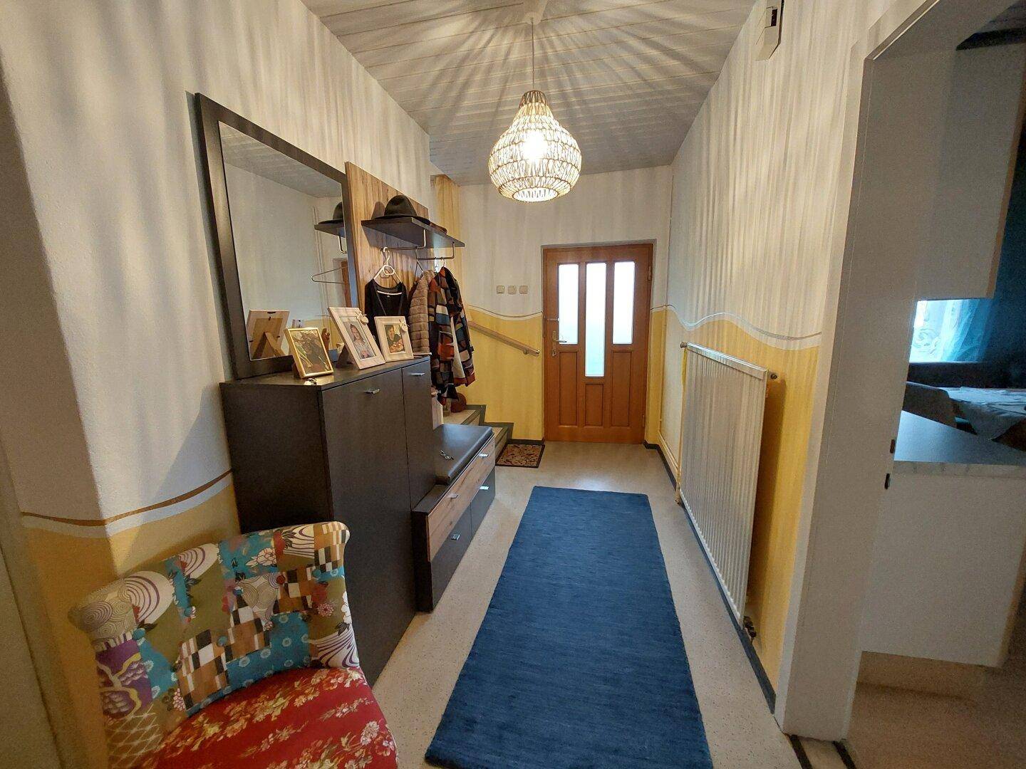 Heller Eingangsbereich mit Garderobe, Spiegel und dekorativer Beleuchtung, die eine einladende Atmosphäre schafft.