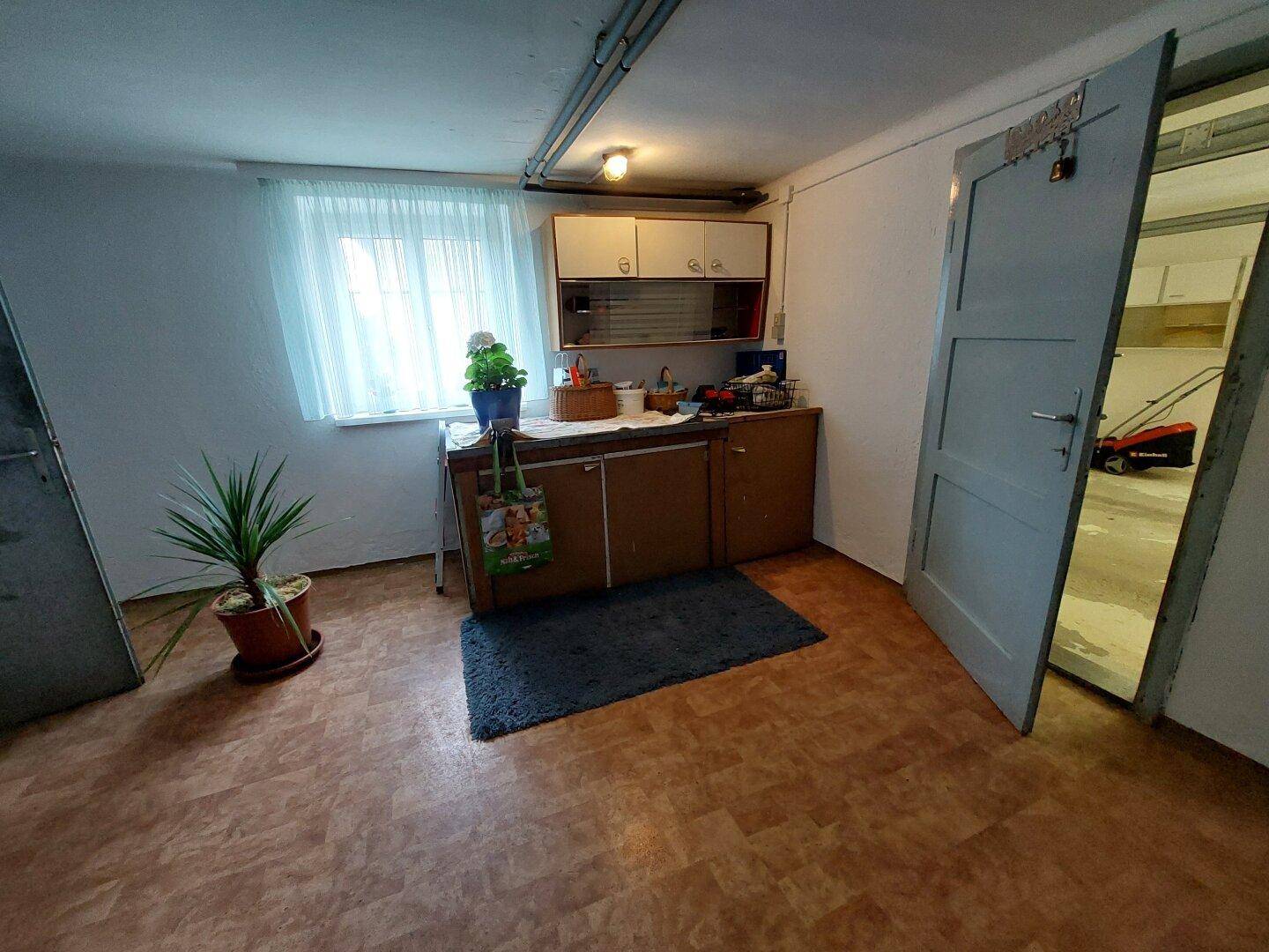 Praktischer Hauswirtschaftsraum im Untergeschoss mit Spüle, Schränken und einem kleinen Fenster für Tageslicht.