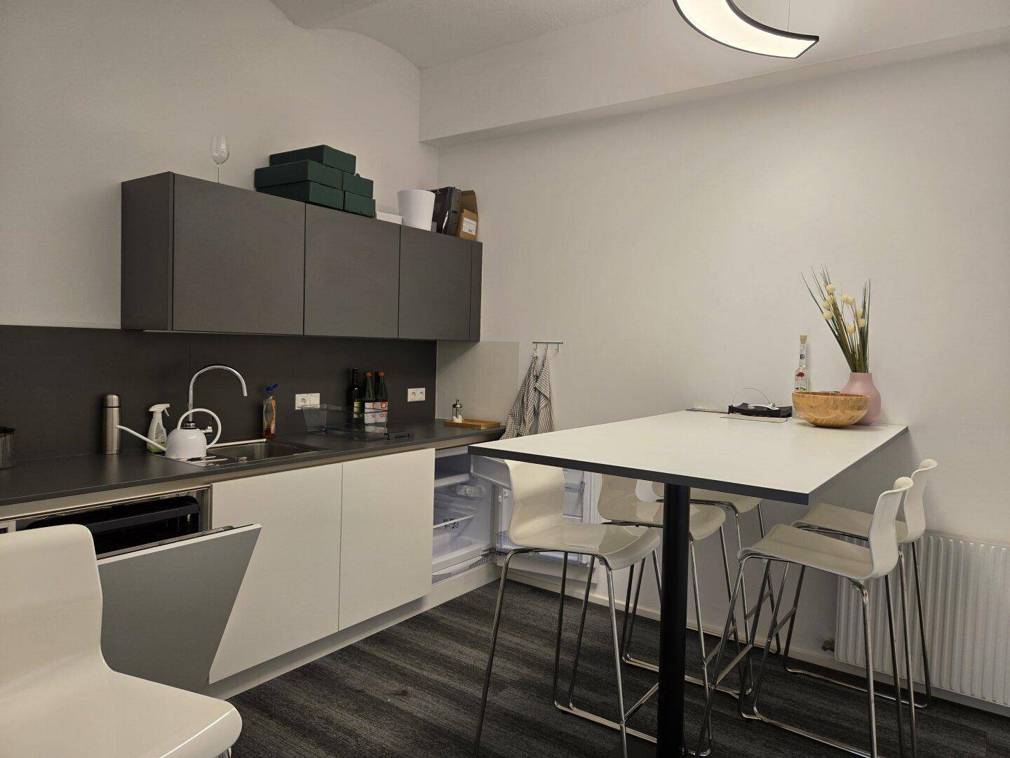 Kleine Küchenzeile mit Spüle, Kühlschrank und Bartisch für Pausen.