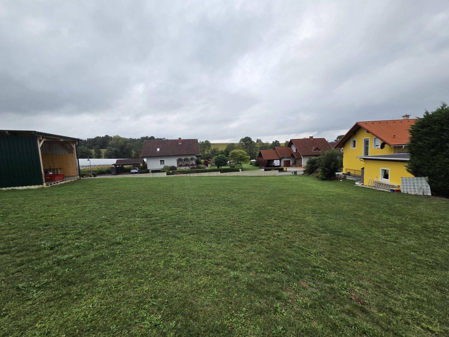 Weitläufige Rasenfläche mit mehreren Häusern im Hintergrund, die eine ländliche Umgebung zeigen.