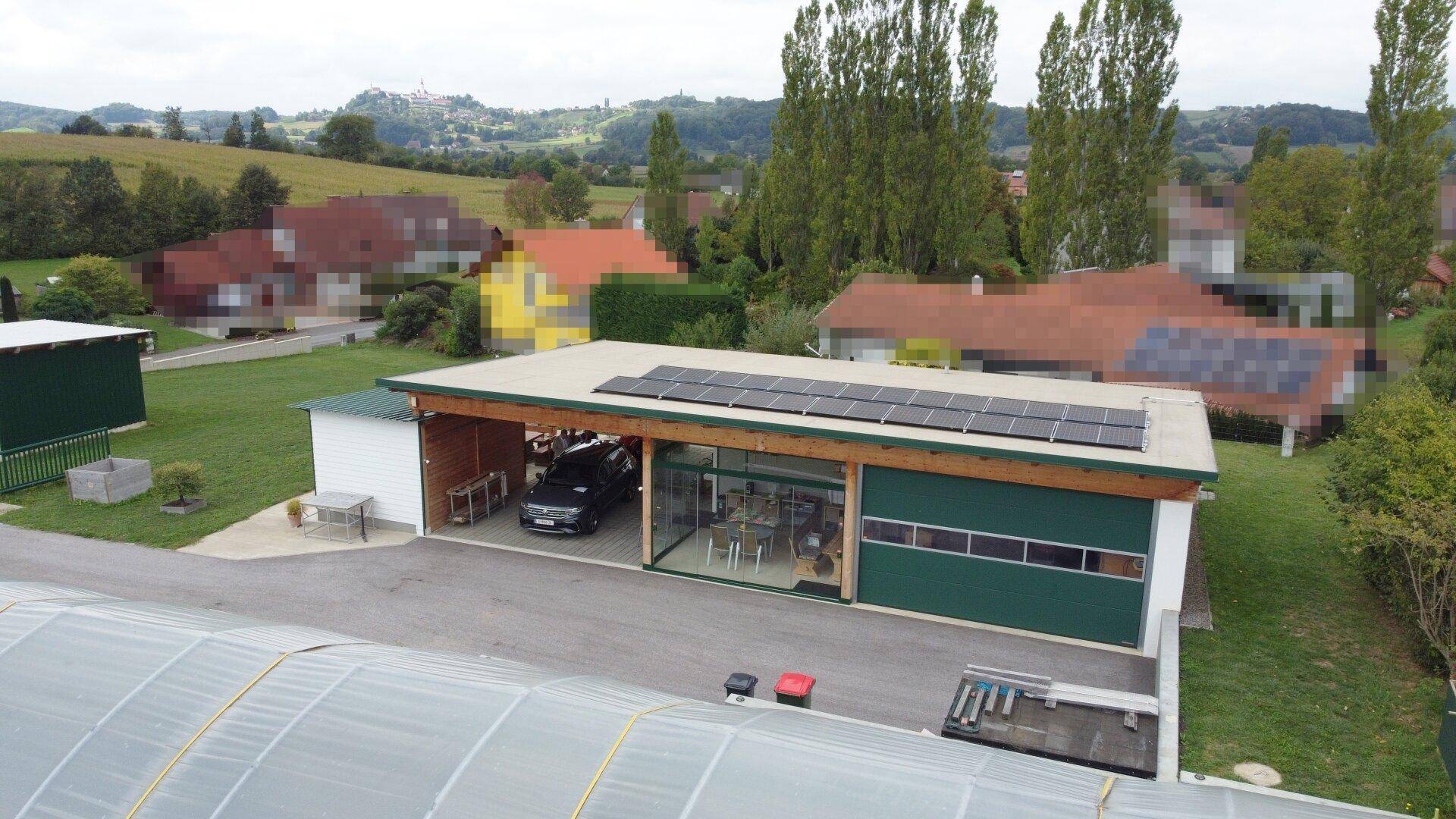 Detaillierte Luftaufnahme des Gebäudes mit Solaranlage, Carport und verglastem Bereich, umgeben von Natur.