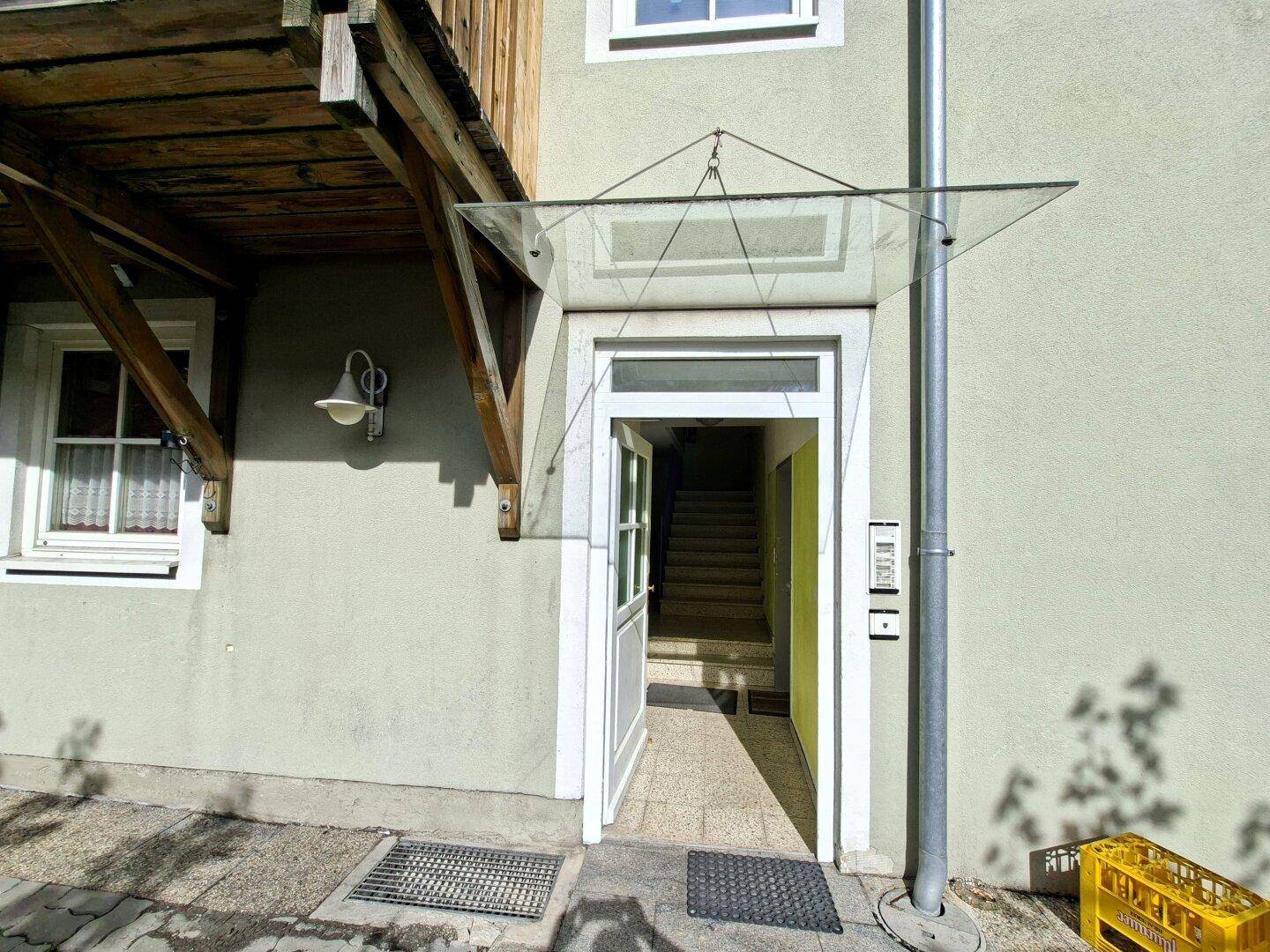 Eingangsbereich eines Gebäudes mit Glastürüberdachung und Zugang zum Treppenhaus.