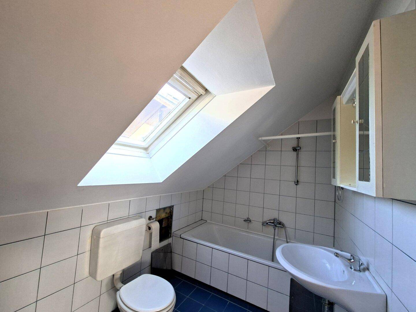 Badezimmer im Dachgeschoss mit Badewanne, WC, Waschbecken und einem Dachfenster für natürliche Belichtung.