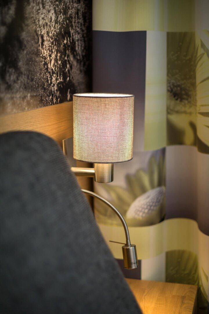 Nahaufnahme einer modernen Nachttischlampe mit Stoffschirm in einem gemütlichen Schlafzimmer.