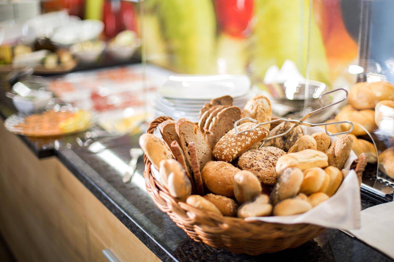 Nahaufnahme eines Korbs mit frischen Brötchen und Brot auf dem Frühstücksbuffet.