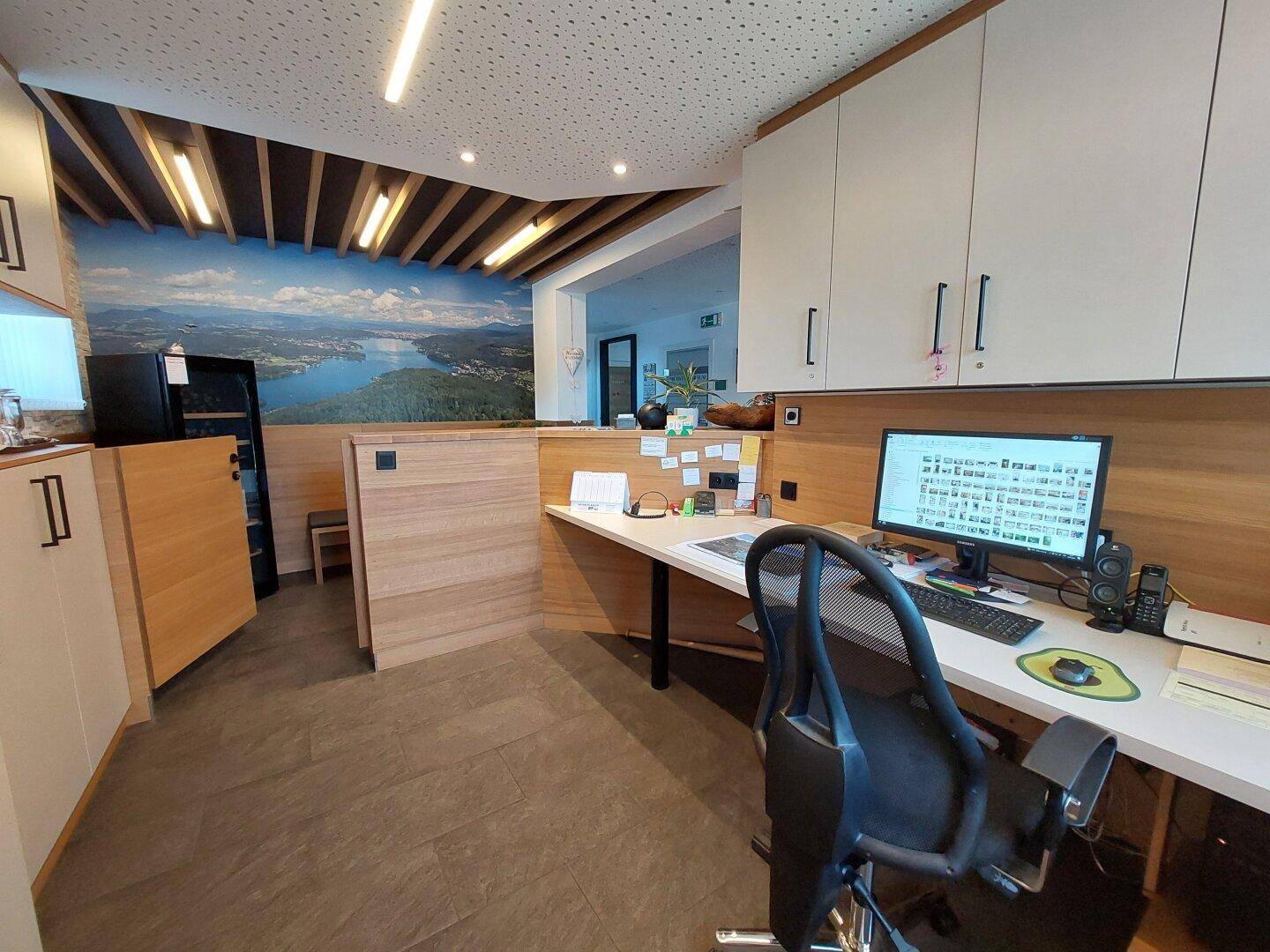 Bürobereich hinter der Rezeption mit Computerarbeitsplatz, Holzmöbeln und Wandbild.