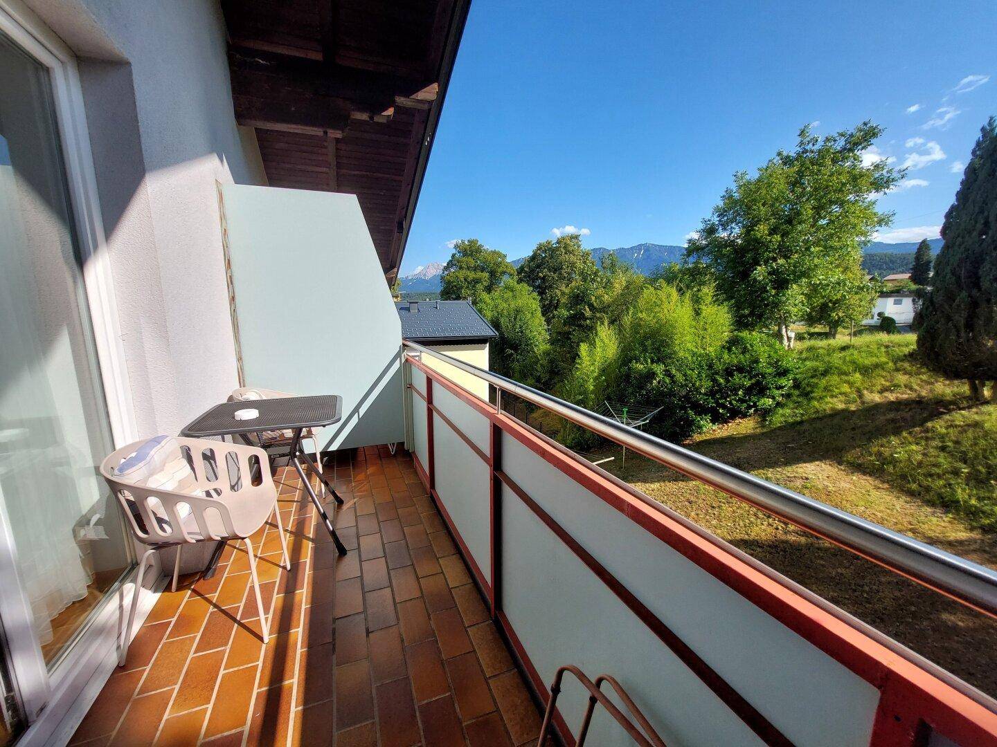 Ein kleiner Balkon mit Terrakottafliesen und Sitzgelegenheiten, bietet einen weiten Blick in die Natur.