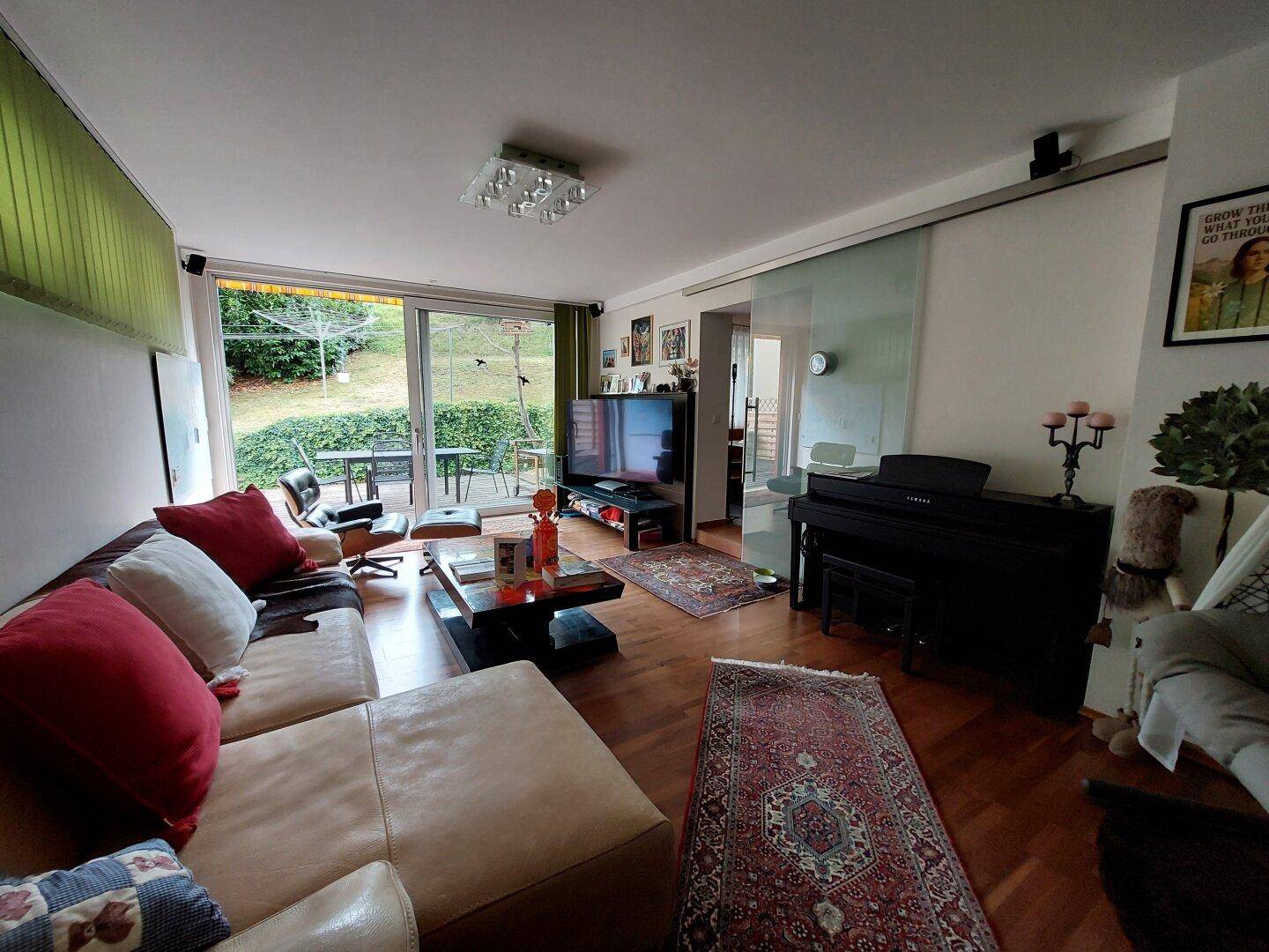 Helles Wohnzimmer mit Zugang zur Terrasse, Holzboden und bequemen Sitzgelegenheiten.