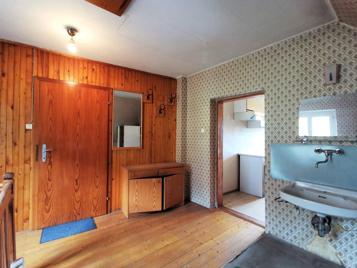 Eingangsbereich mit Holzvertäfelung, Waschbecken und Zugang zu weiteren Räumen im Landhausstil.