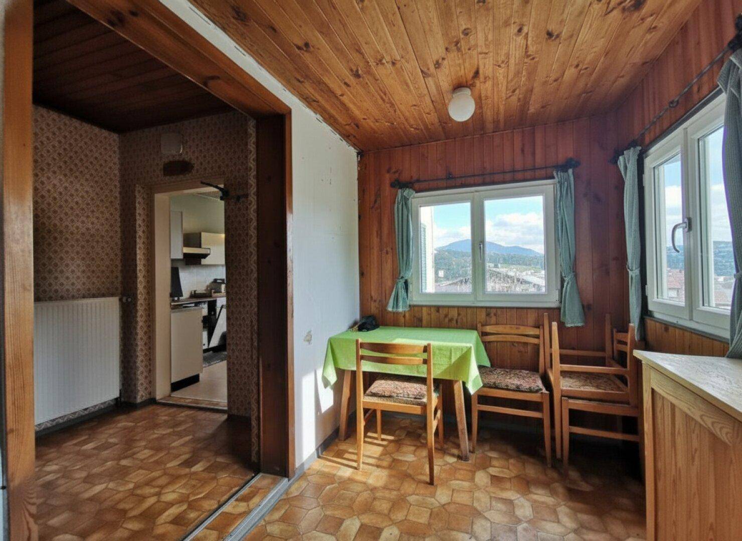 Gemütlicher Essbereich mit Holzvertäfelung, gemusterter Tapete und Blick auf die umliegende Landschaft.