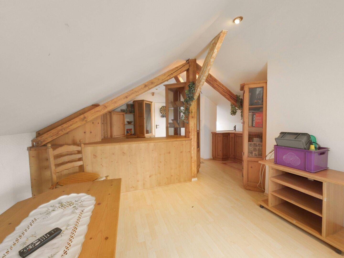 Ausgebauter Dachboden mit sichtbaren Holzsparren, Holzböden und schrägen Decken.