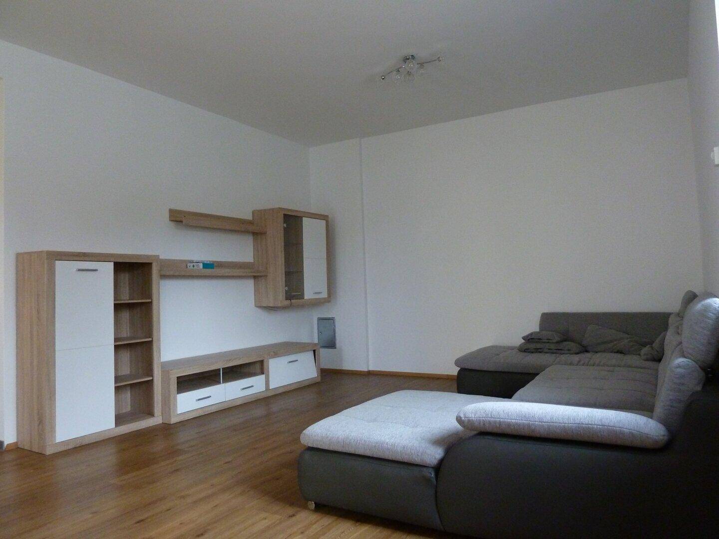 Geräumiges Wohnzimmer mit einem Ecksofa und einer modernen Wohnwand aus Holz und Weiß.