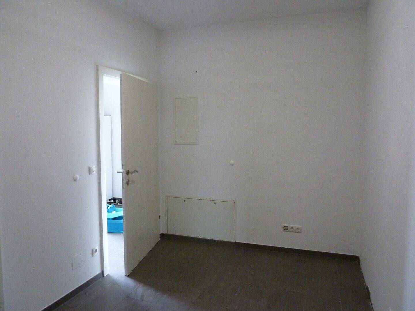 Leerer Raum mit Fliesenboden und einer Tür, vielseitig nutzbar.