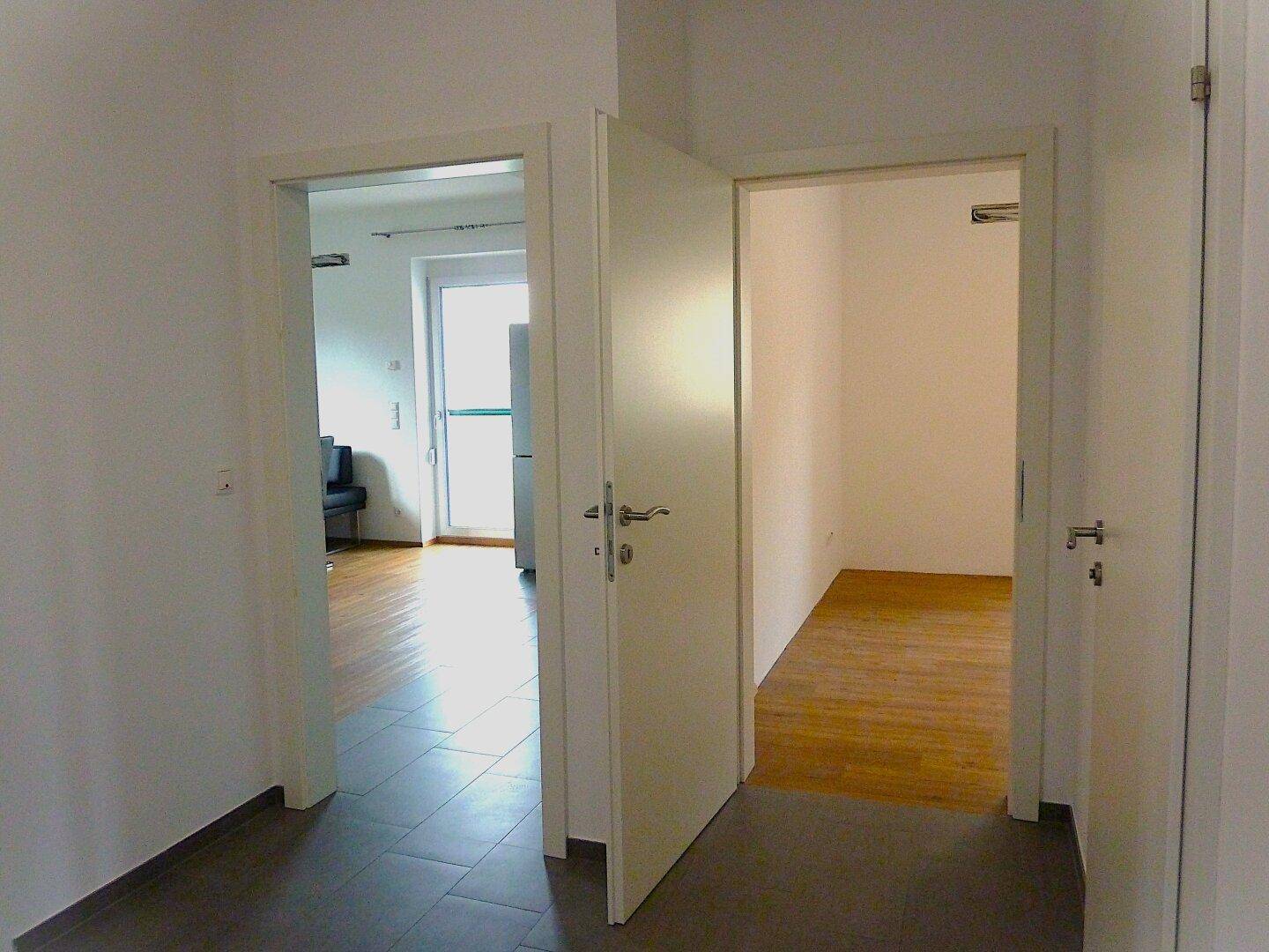 Heller Flur mit Fliesenboden und offenen Türen, die zu weiteren Räumen führen.