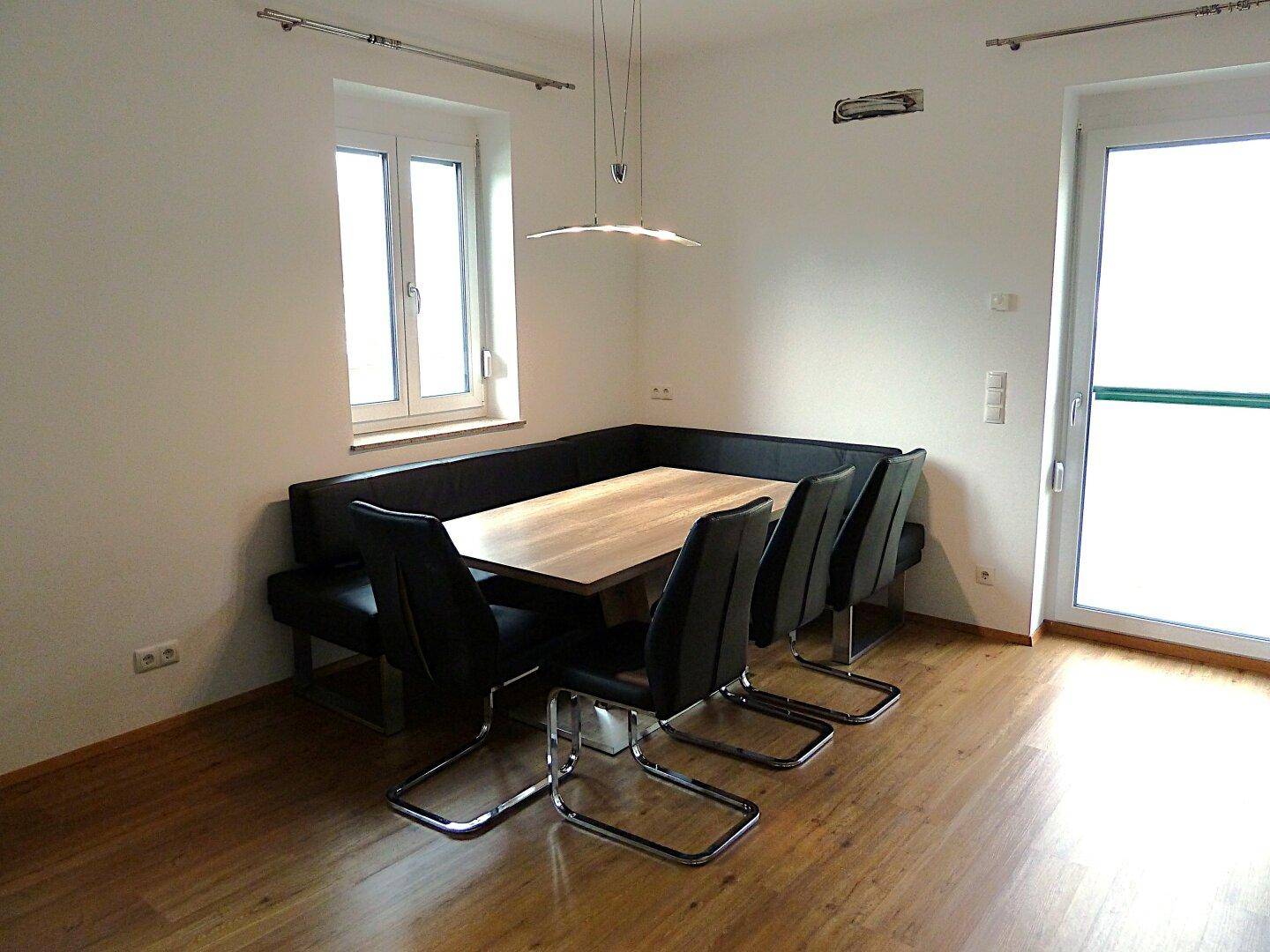 Gemütlicher Essbereich mit Eckbank, Esstisch und Stühlen, beleuchtet durch ein Fenster.