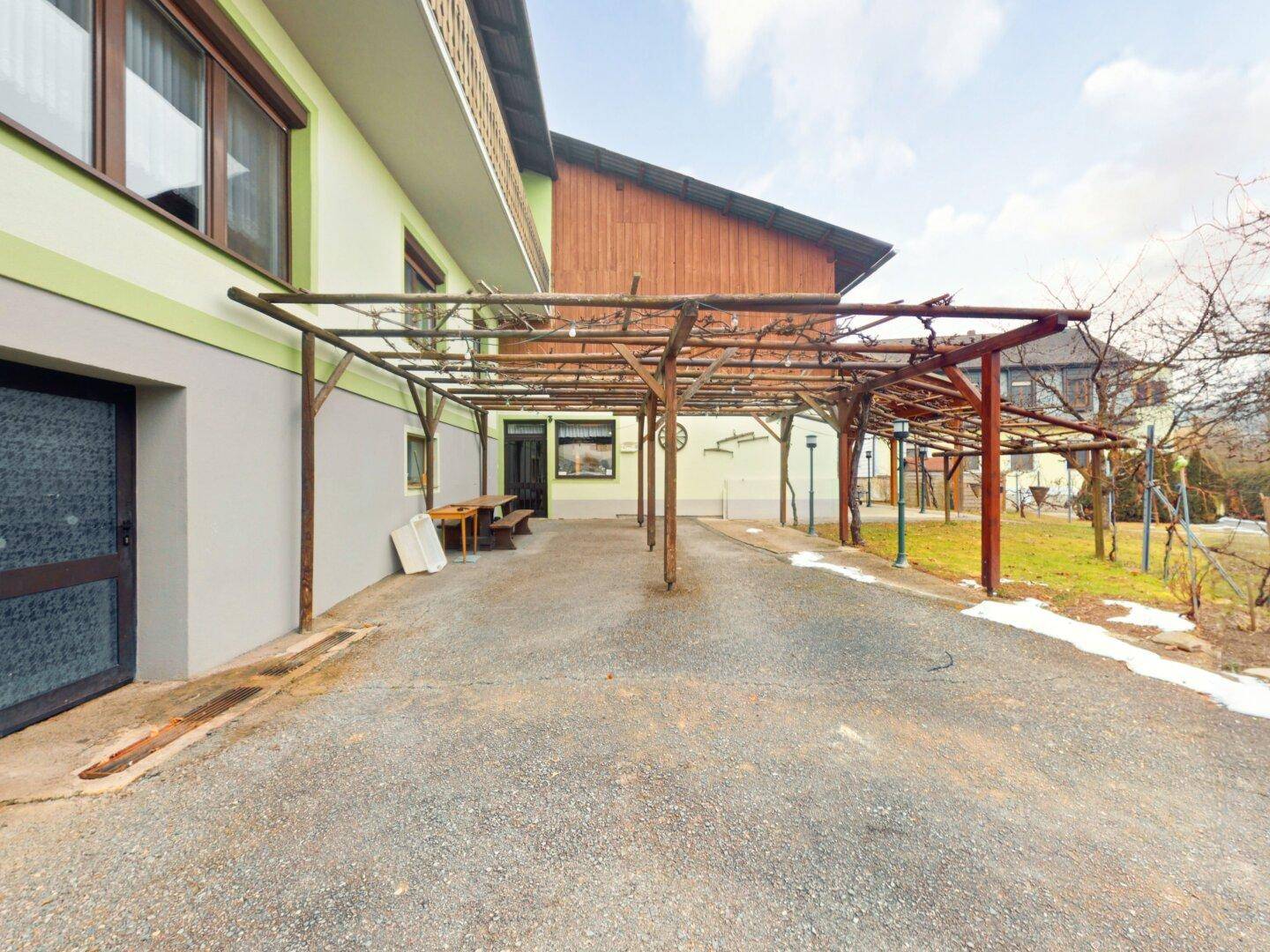 Überdachter Außenbereich, der als Carport oder Lagerfläche genutzt werden könnte, neben dem Gebäude.