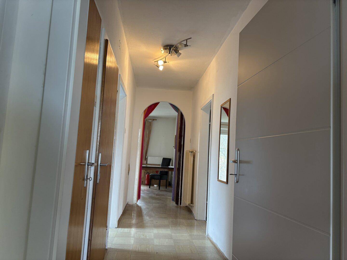 Heller Flur mit Fliesenboden und Holztüren, der zu weiteren Räumen führt.