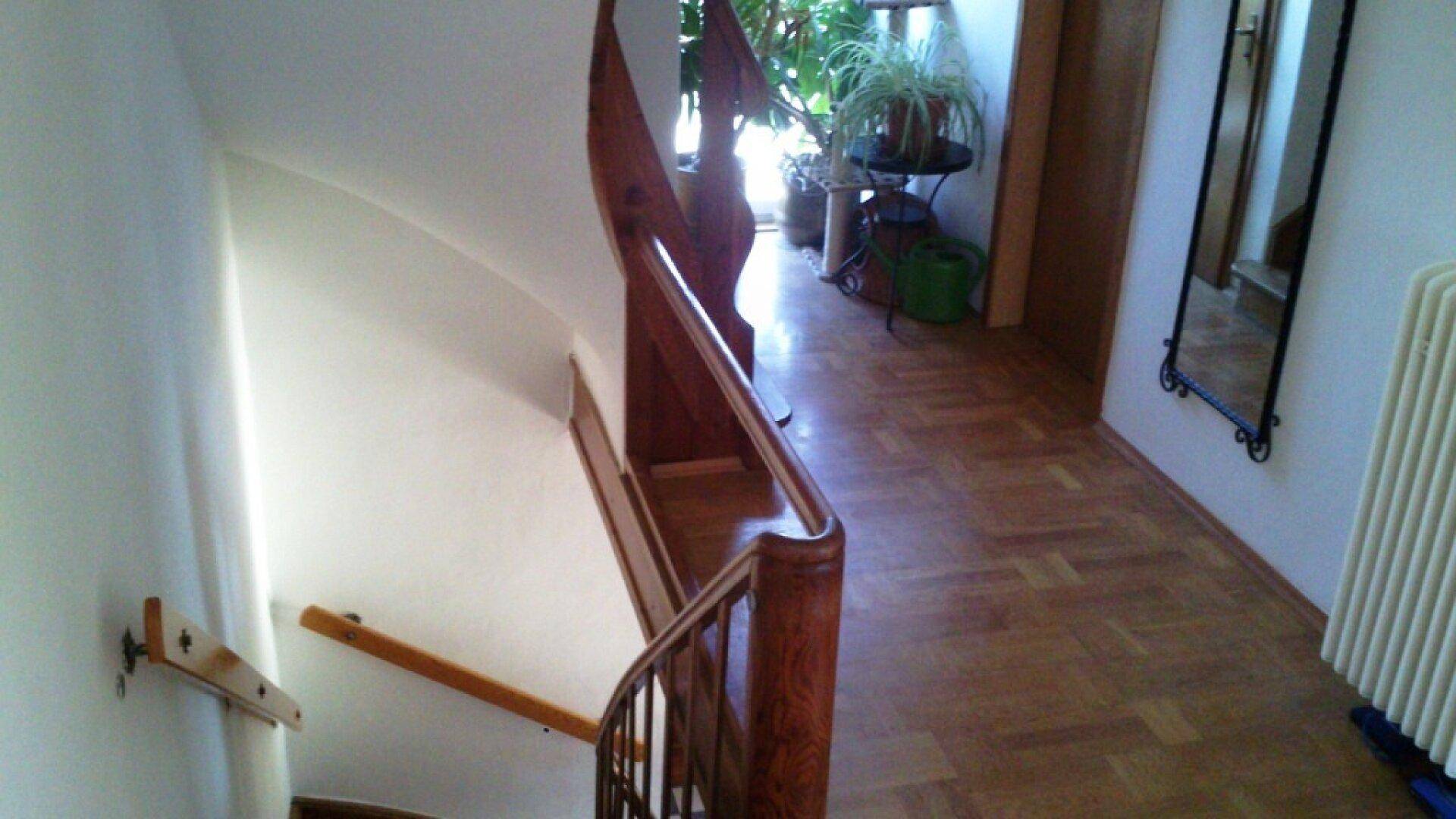 Heller Flur mit Holzparkett und geschwungener Holztreppe zum Obergeschoss.