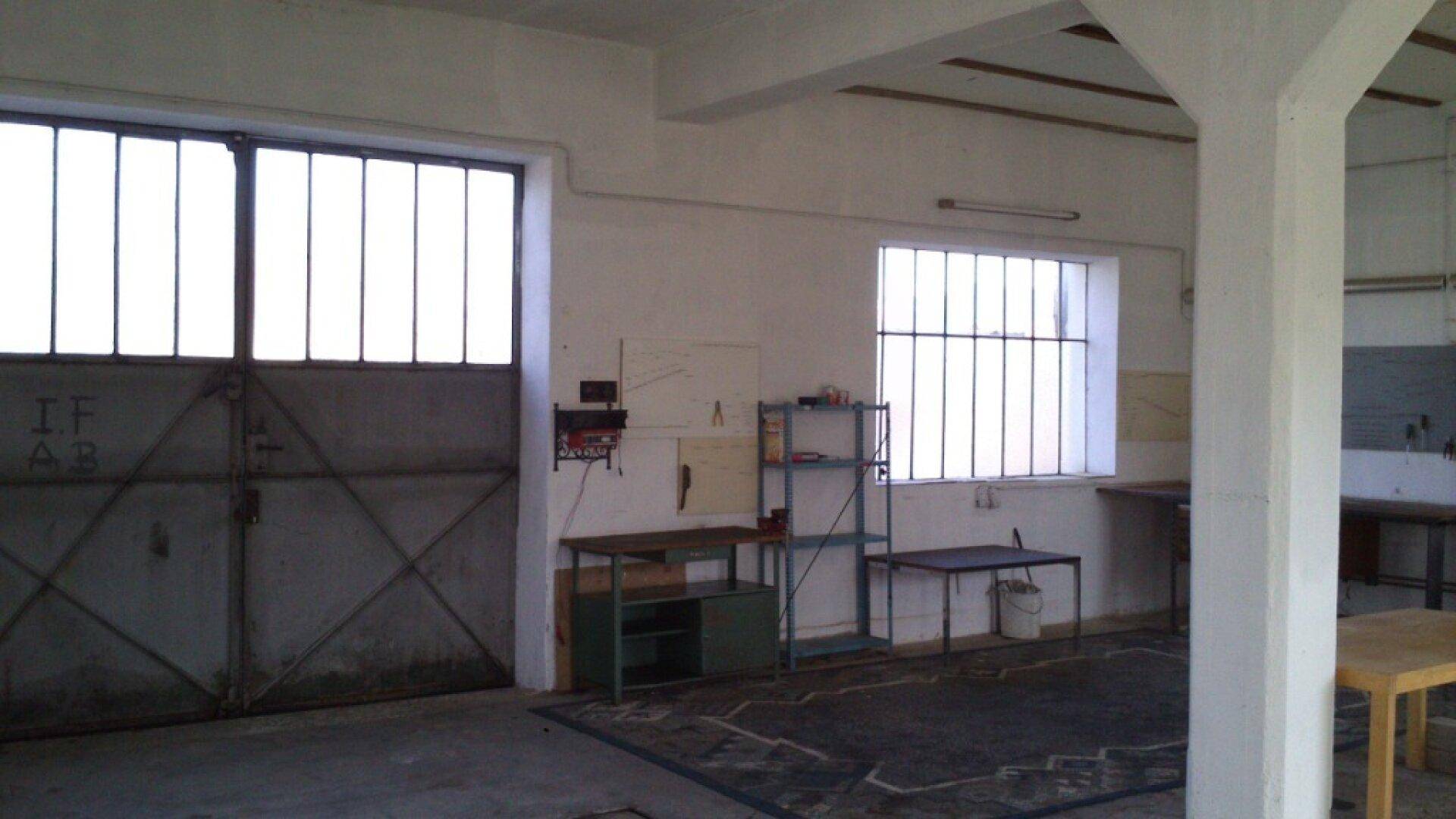 Geräumige Garage mit großen Toren und Fenstern, ideal für Fahrzeuge oder Lagerung.