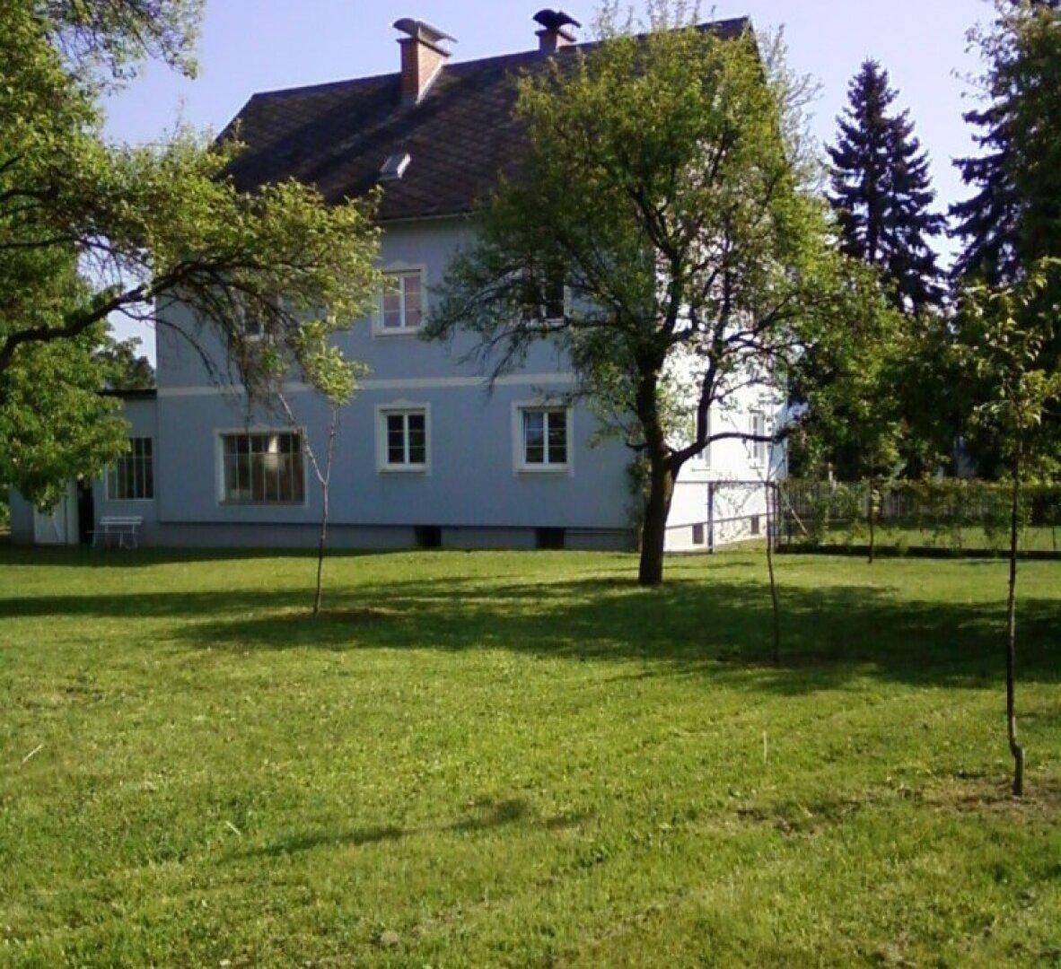 Große, gepflegte Rasenfläche mit Obstbäumen und dem Wohnhaus im Hintergrund.