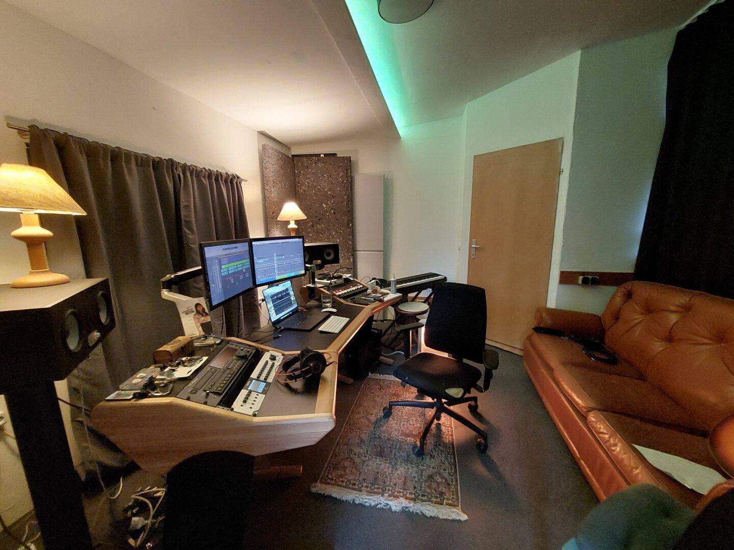 Professioneller Arbeitsplatz mit mehreren Monitoren, Ledersofa und indirekter Beleuchtung.