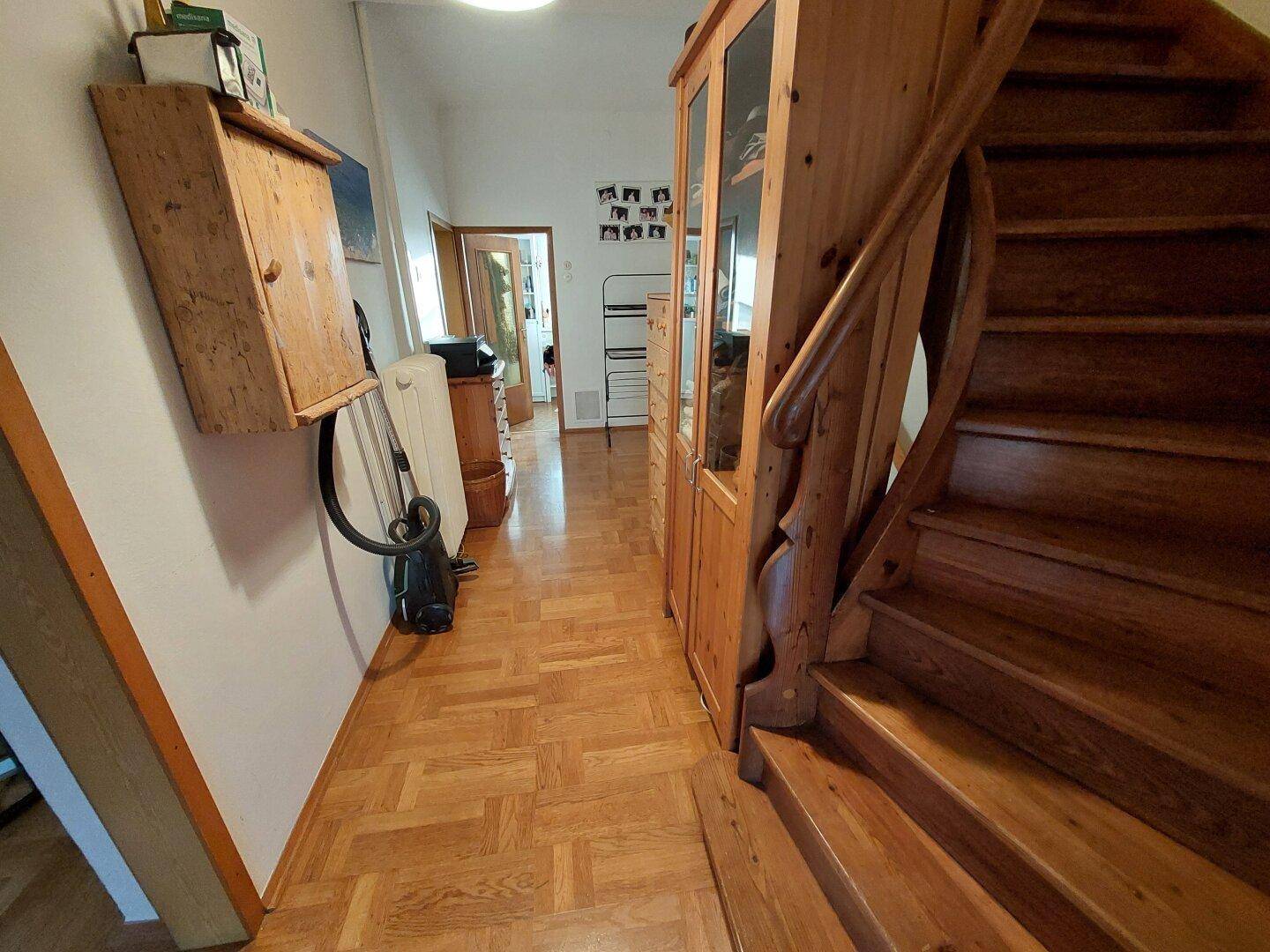 Langer Flur mit Holzparkett, Holzschrank und Zugang zu weiteren Räumen.