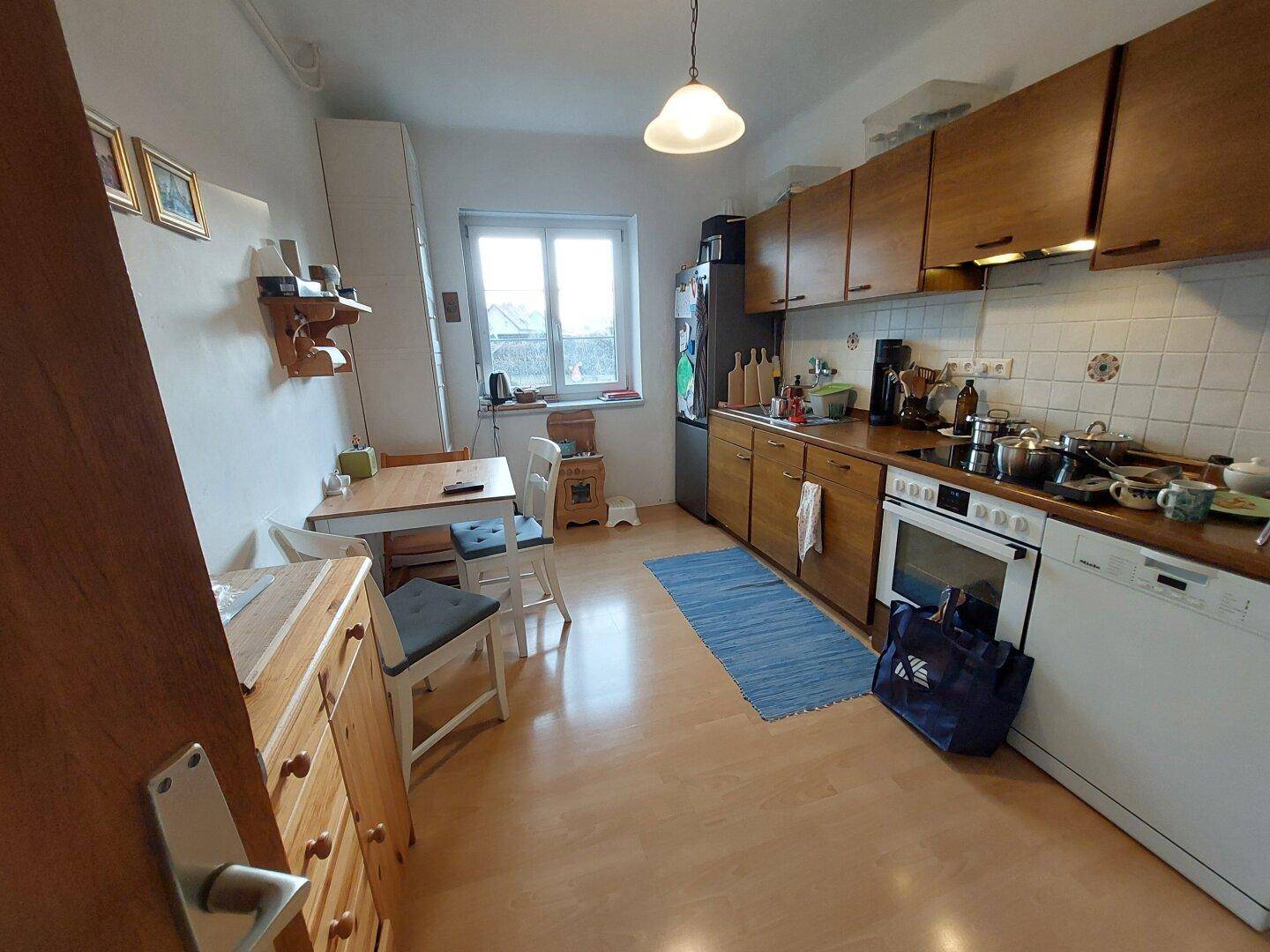 Funktionale Wohnküche mit Holzschränken, Essbereich und Fenster.