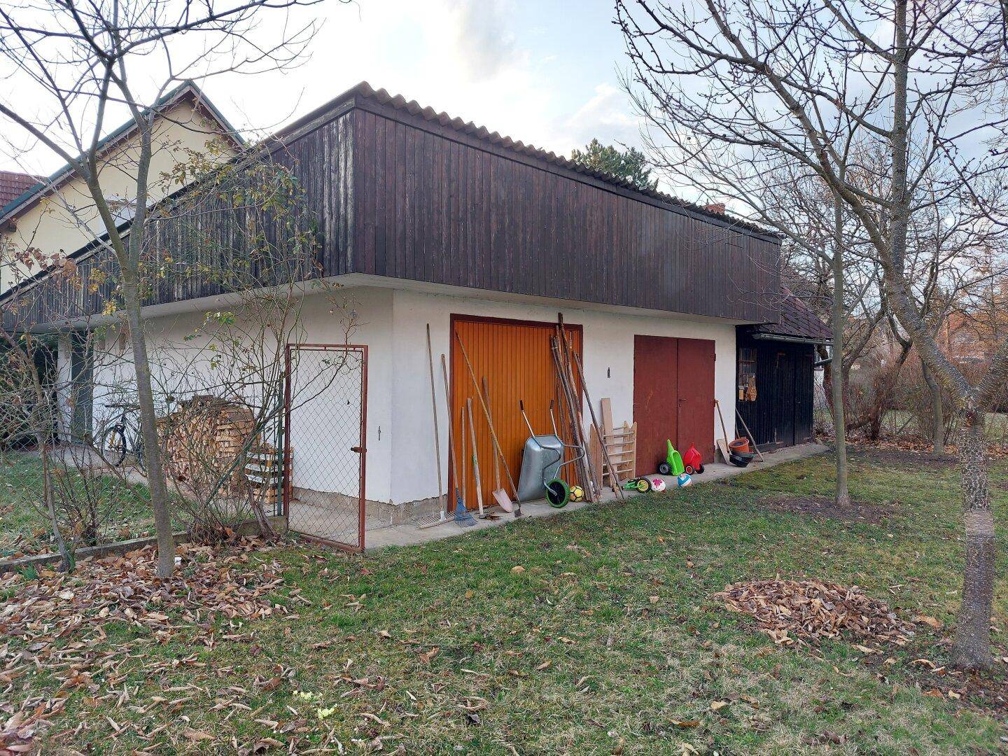 Nebengebäude mit mehreren Garagentoren und Holzverkleidung, umgeben von Grün.