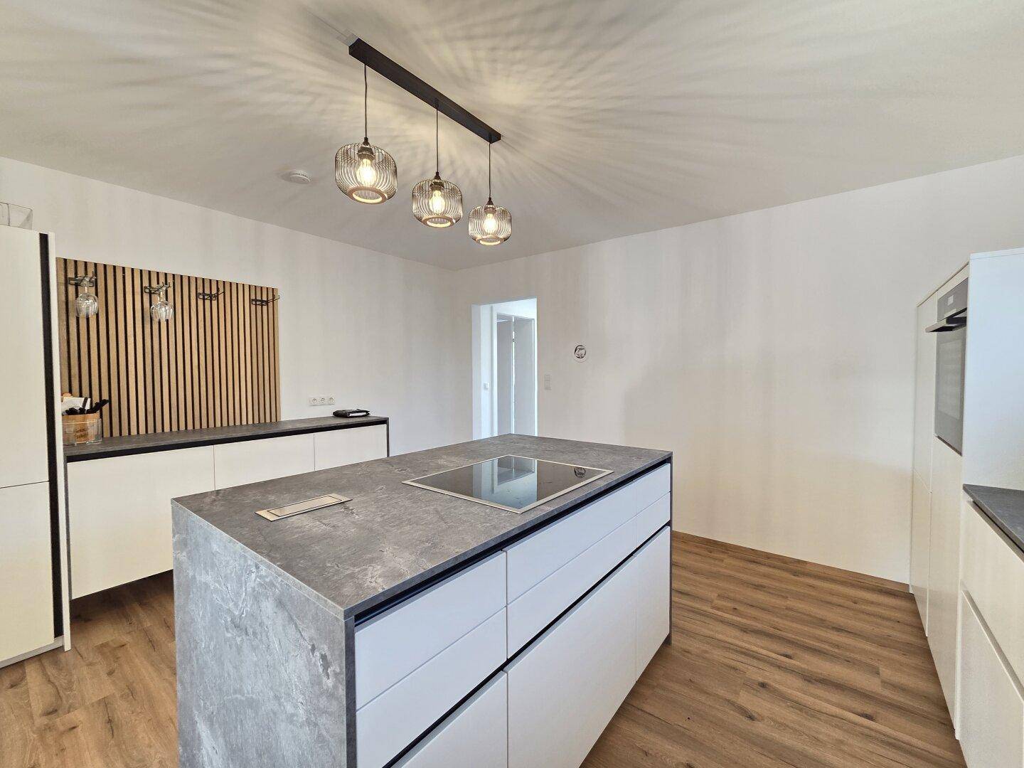 Stilvolle Kücheninsel mit Induktionskochfeld und viel Stauraum, ergänzt durch eine moderne Wandverkleidung.