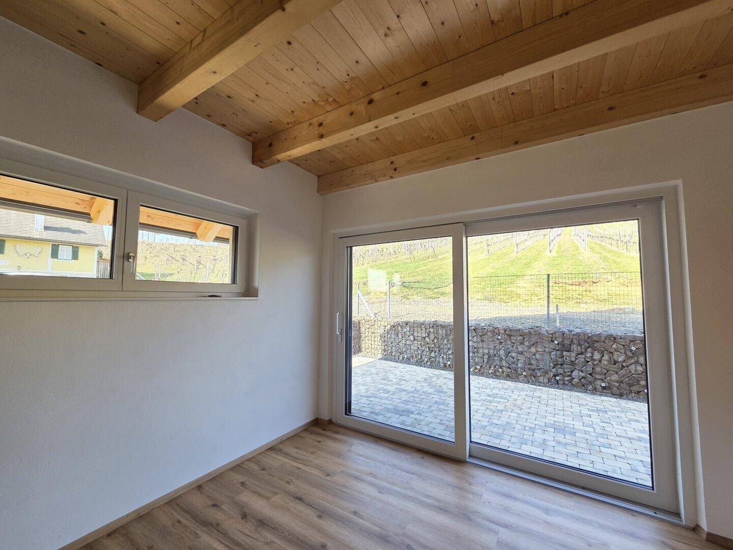 Heller Raum mit großen Schiebetüren zur Terrasse und Blick auf die grüne Umgebung.