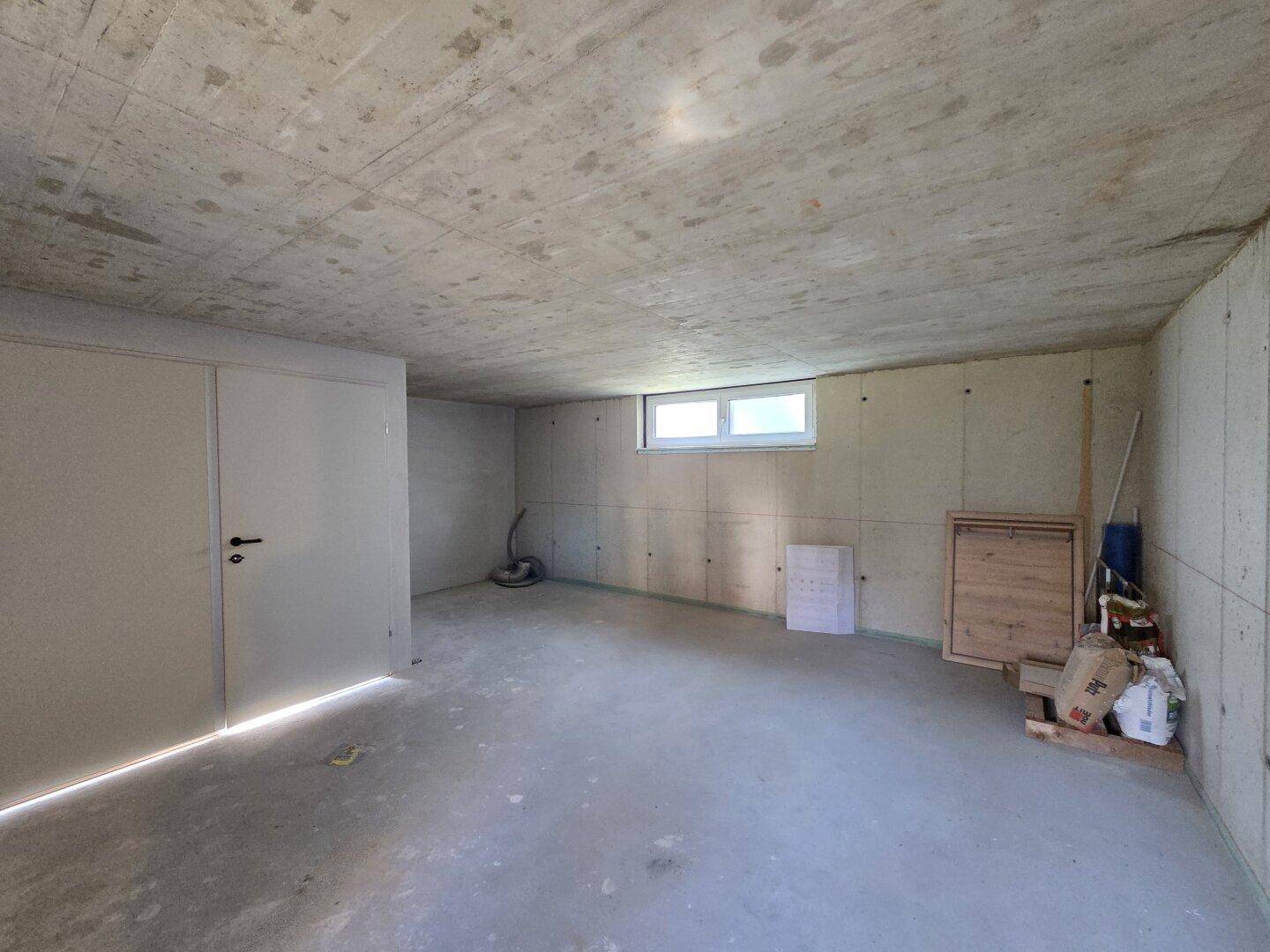 Geräumiger Kellerraum mit Betonboden und einem kleinen Fenster für Belüftung und Tageslicht.