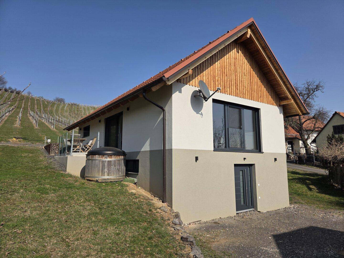 Seitenansicht des modernen Hauses mit zweifarbiger Fassade und Satellitenschüssel.