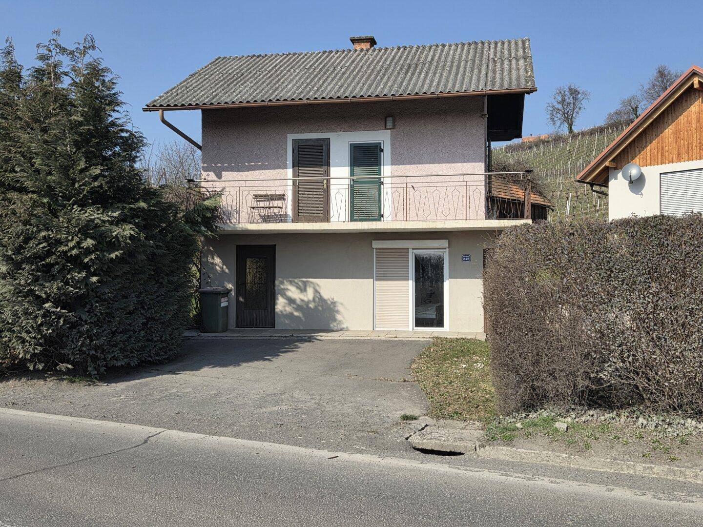 Vorderansicht des Hauses mit Balkon, Außentreppe und Zufahrt.