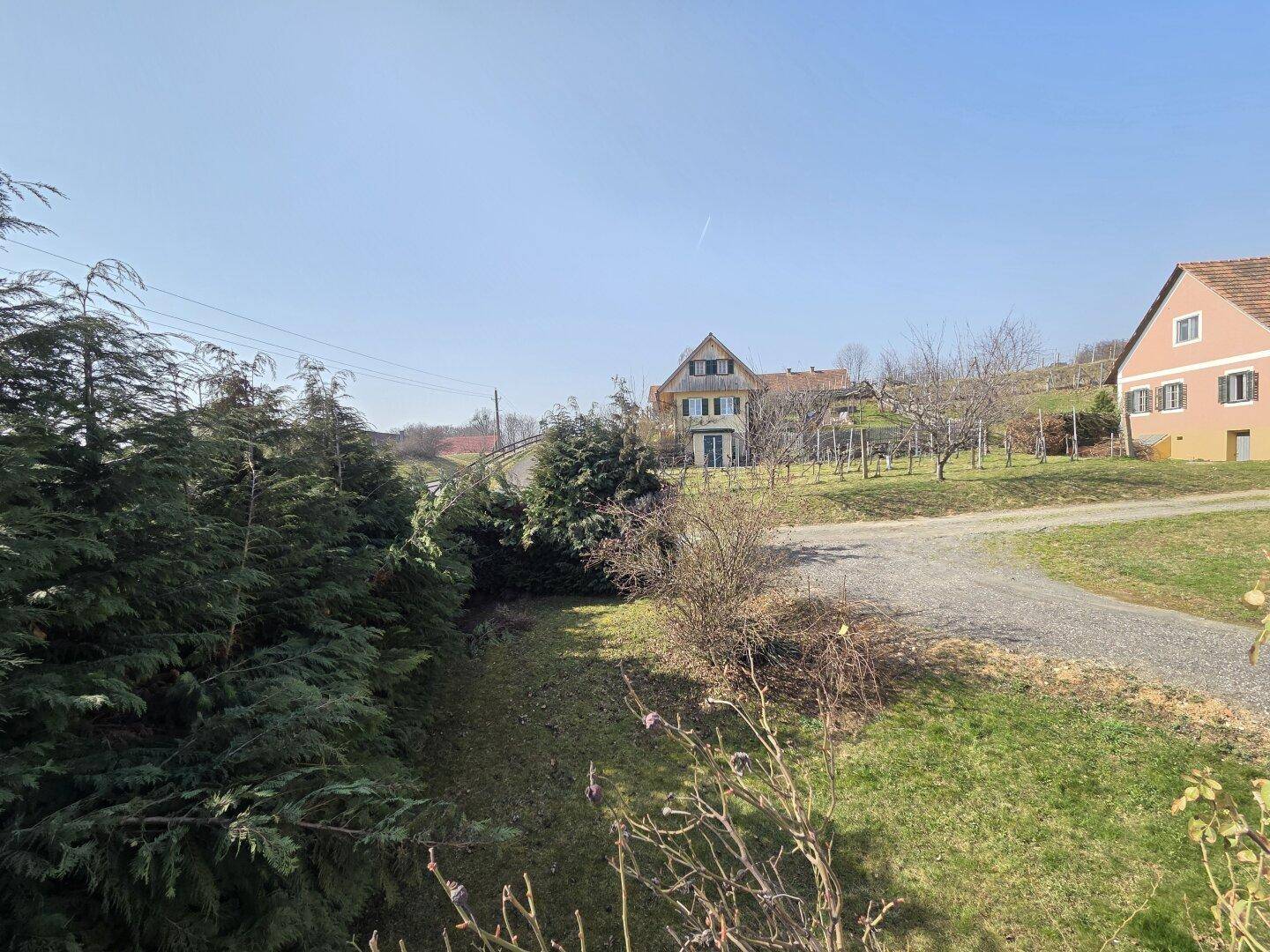 Weitläufige Landschaft mit Bäumen, Wiesen und Häusern in der Ferne.