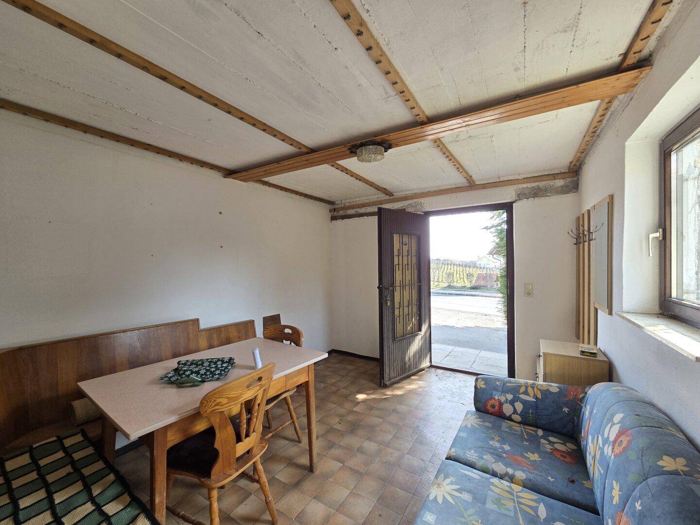 Rustikaler Wohnbereich mit Holztisch, Sitzbank und Zugang zum Außenbereich.