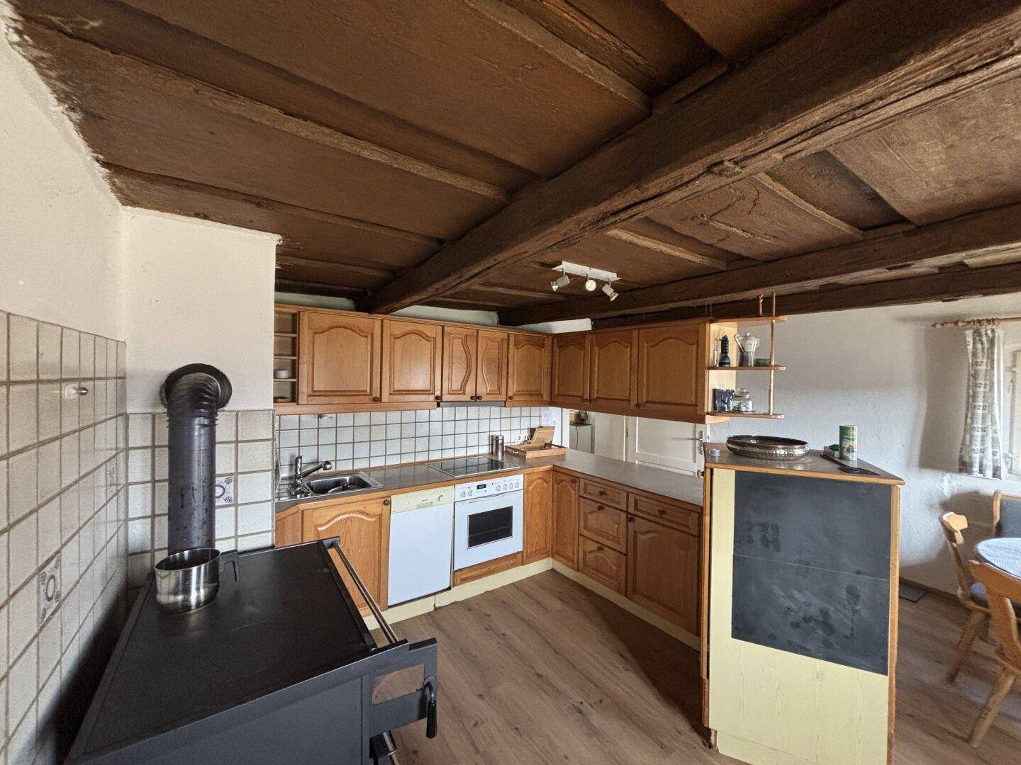 Geräumige Küche mit Holzmöbeln, Kachelofen und rustikalen Fliesen an der Wand.