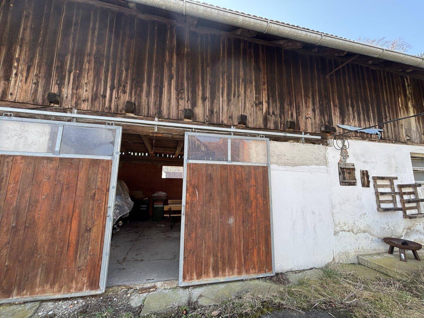 Rustikale Holzfassade eines Nebengebäudes mit großen Scheunentoren.