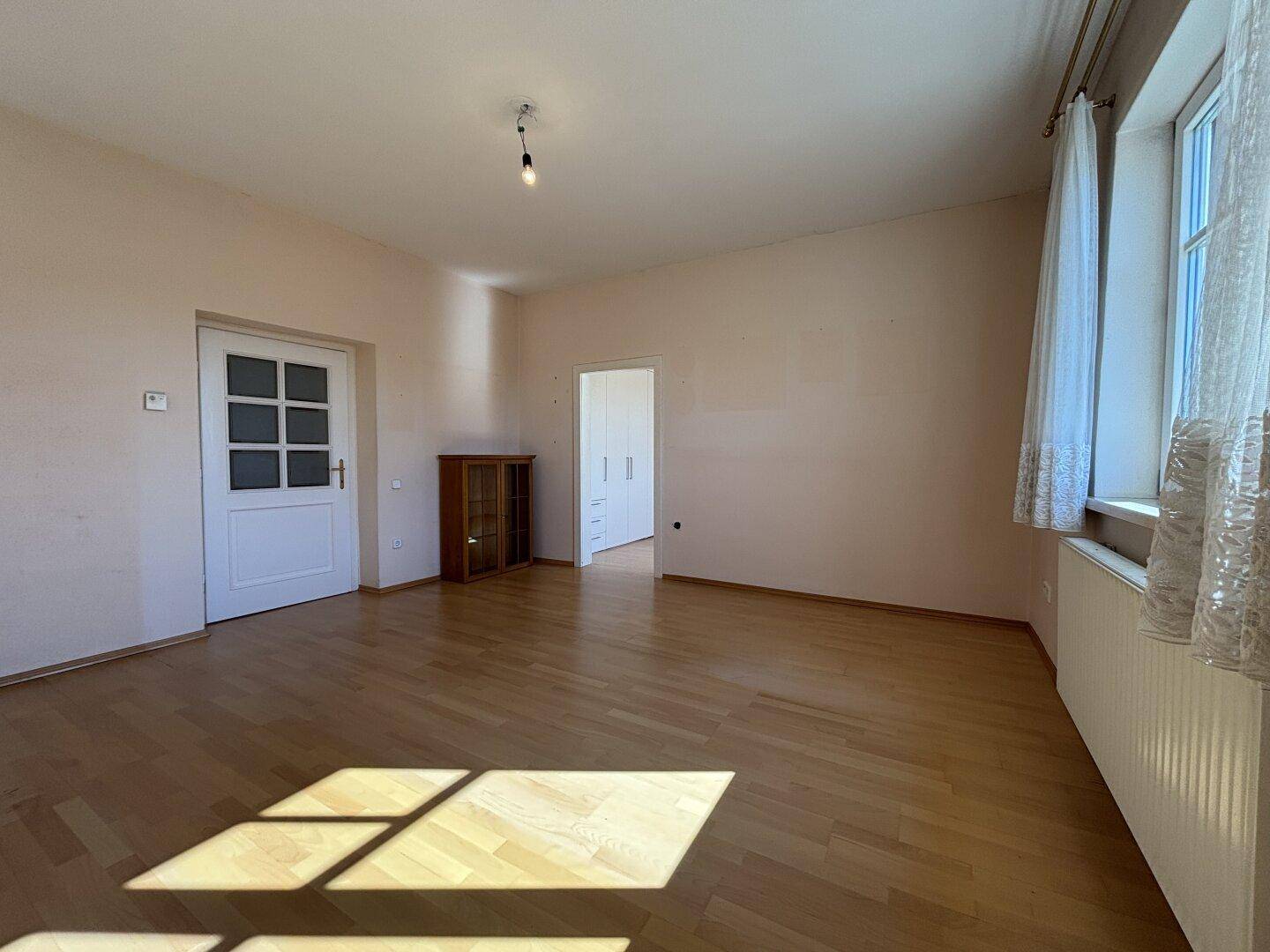 Heller Raum mit Parkettboden, großen Fenstern und viel Tageslicht.