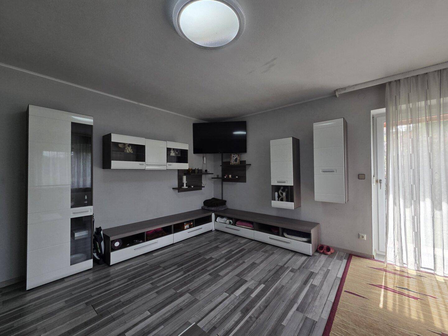 Wohnzimmer mit Laminatboden, Wandmontage für Fernseher und modernen Schränken für Stauraum.