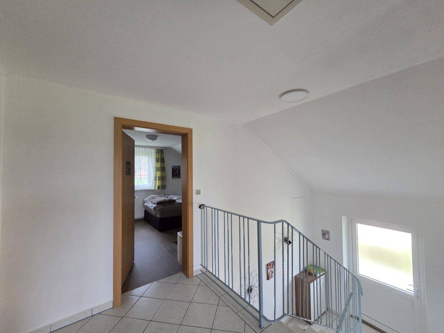 Heller Flur im Obergeschoss mit Zugang zu einem Schlafzimmer und Blick auf das Treppenhaus.