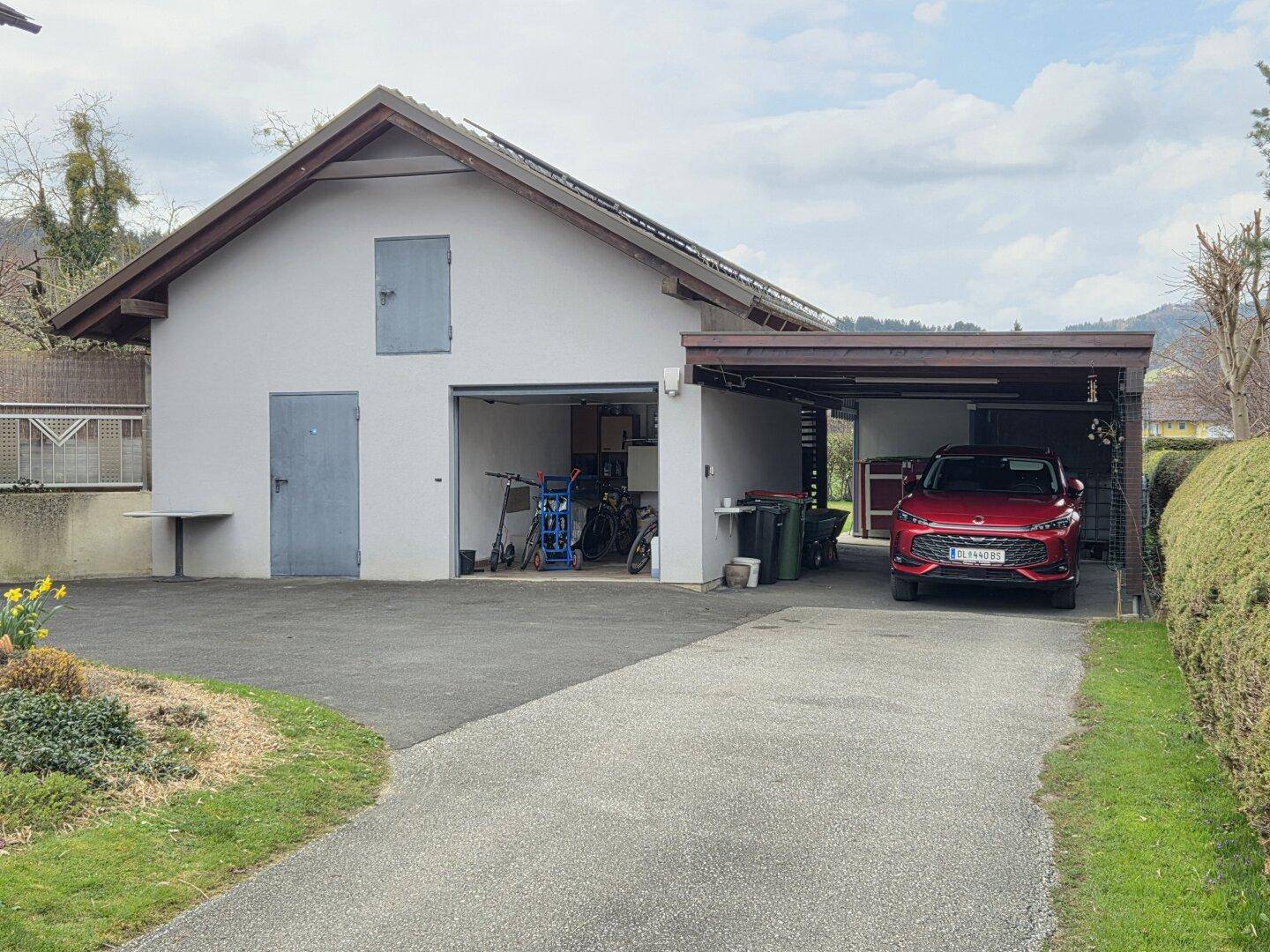 Garage mit Carport und Zufahrt, bietet ausreichend Parkmöglichkeiten für Fahrzeuge.