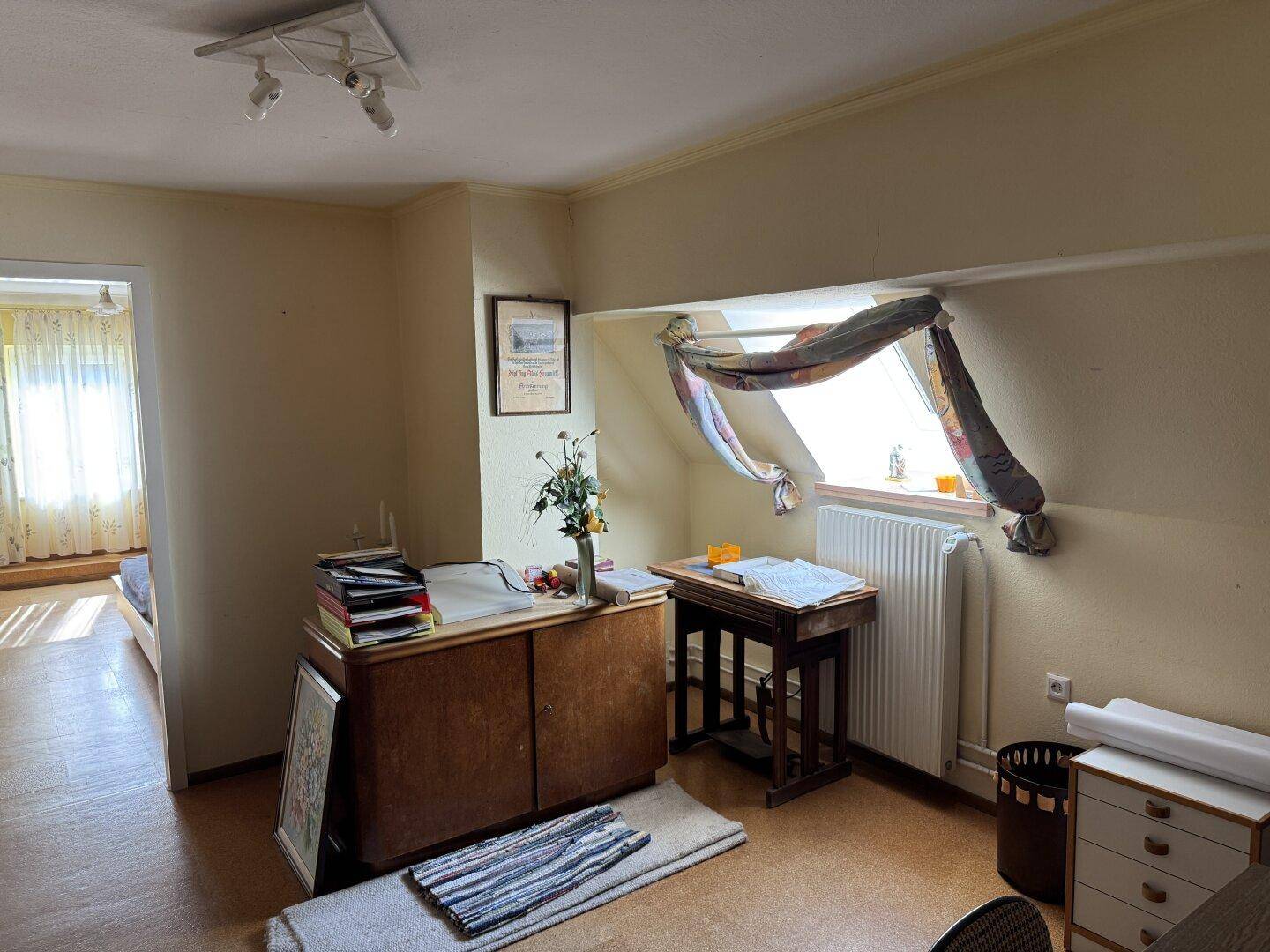 Helles Arbeitszimmer im Dachgeschoss mit Schreibtisch, Stauraum und Dachfenster.