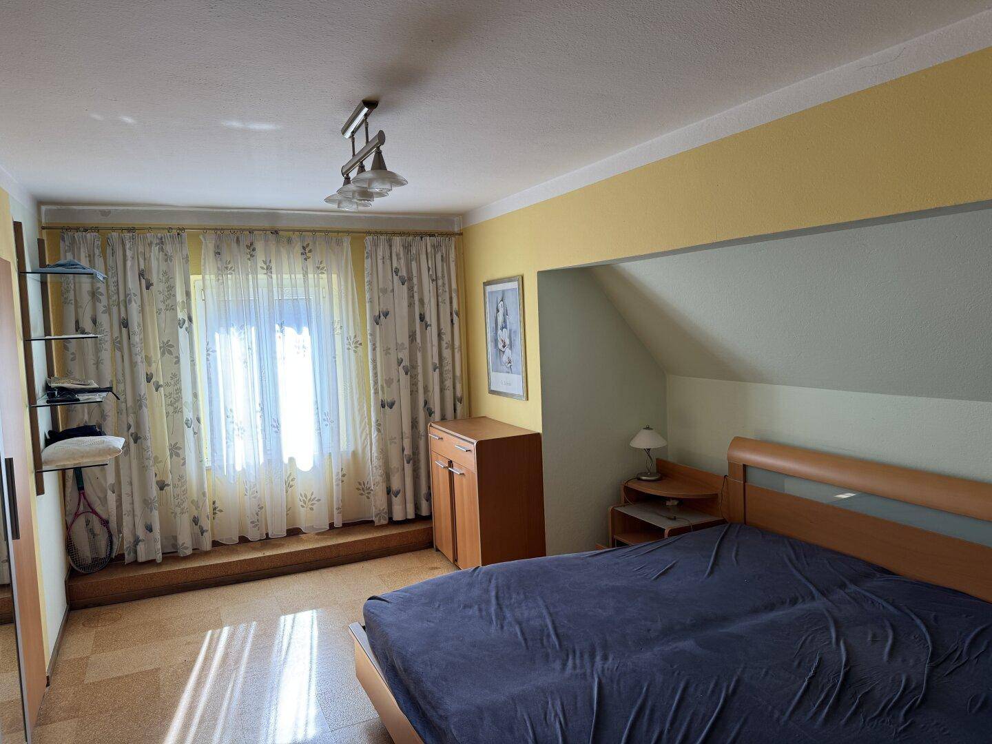 Geräumiges Schlafzimmer mit Doppelbett, Kleiderschrank und großem Fenster.