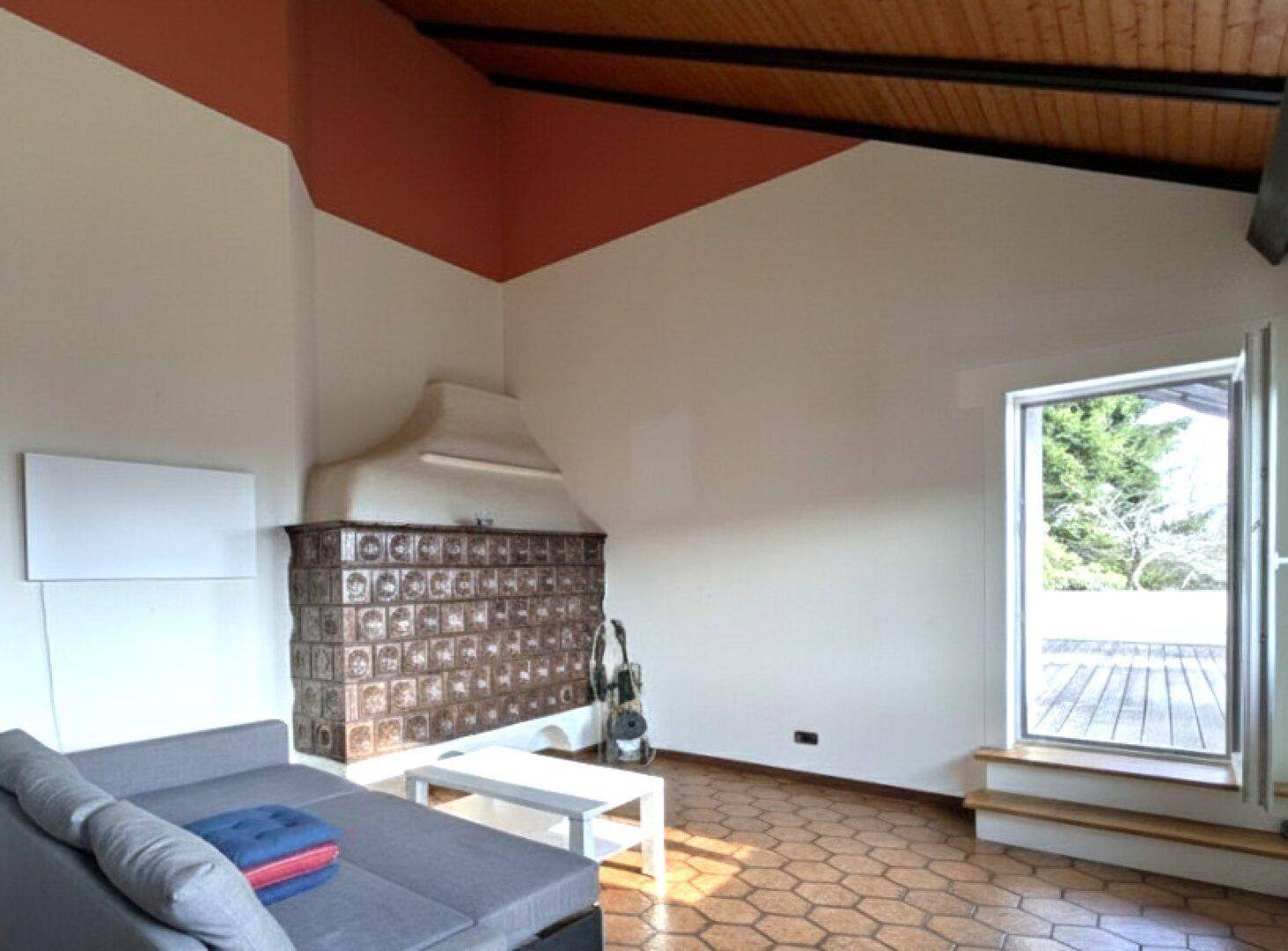 Gemütlicher Wohnbereich mit traditionellem Kachelofen und Zugang zur Terrasse.
