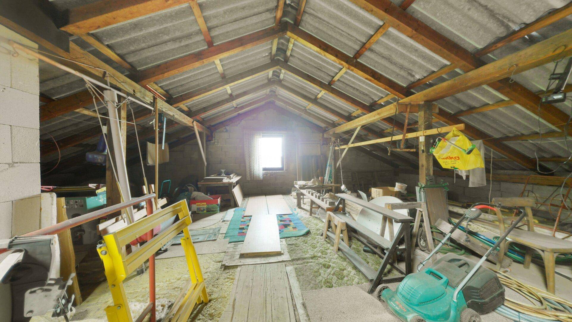 Unausgebauter Dachboden mit sichtbaren Holzbalken und Dachfenster, bietet Ausbaupotenzial.